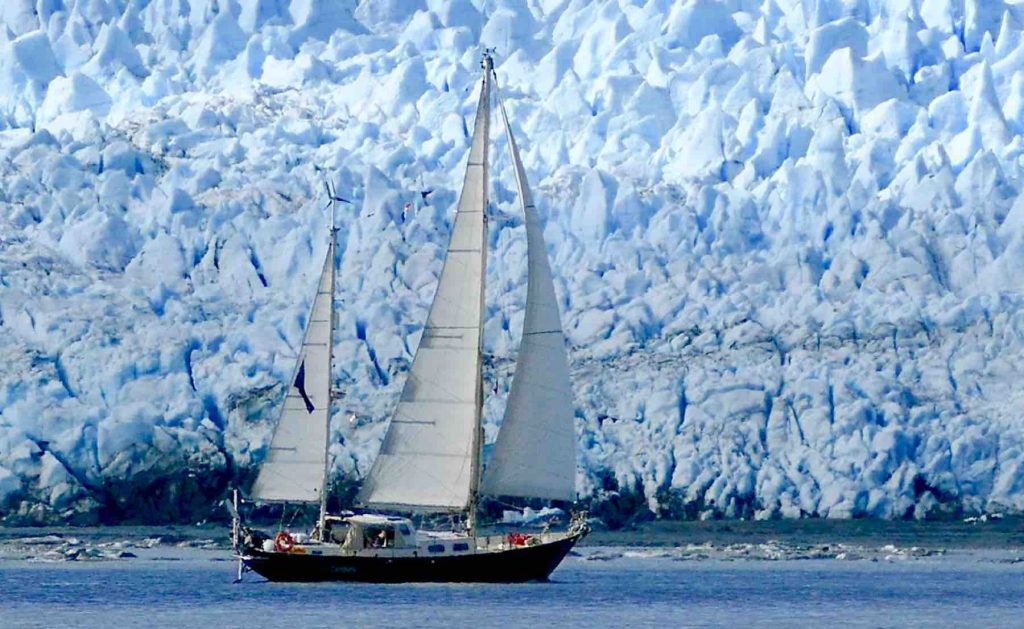 Her seiler båten ved siden av et isfjell i Patagonia, Argentina.
